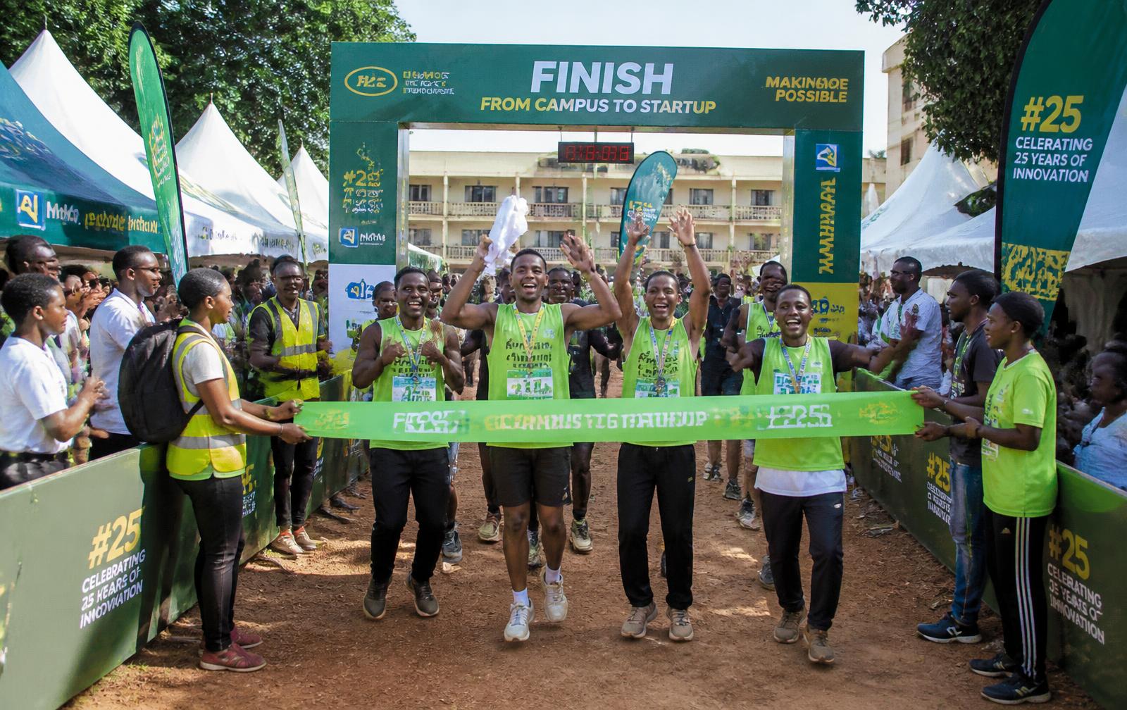 Runners breaking the tape at the campus finish line festival